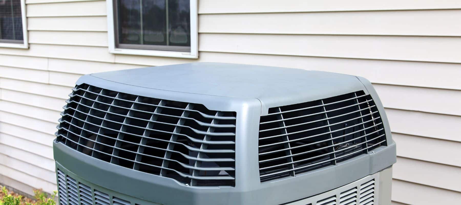a gray outdoor ac unit installed next to a house